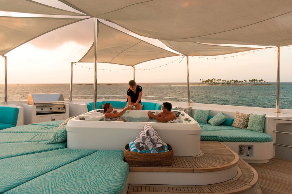 Rhino Superyacht Charter - Couple relaxing in a Jacuzzi while being served drinks