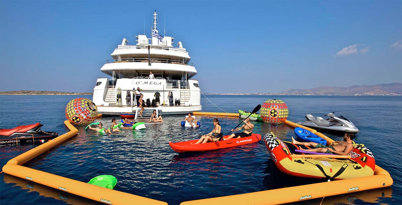 O'Mega Yacht Charter guests lounging in the water with a wide selection of water toys