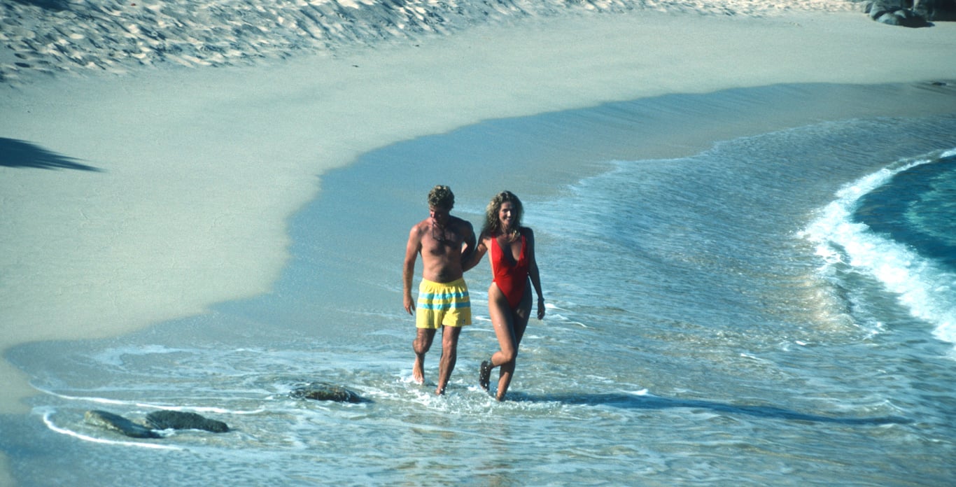 Couple strolls deserted beach in Virgin Gorda, BVI